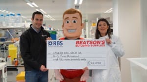 Managing director of Beatson’s Building Supplies, Ross Marshall hands over a giant cheque to PhD student, Clelia Armato at the Cancer Research UK Beatson Institute.